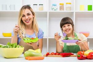 Happy mother and her daughter enjoy making and having healthy meal together at their home. photo