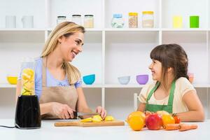 Happy mother and her daughter enjoy making smoothie together at their home. photo