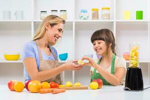 Happy mother and her daughter enjoy making smoothie together at their home. photo