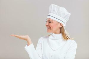 Portrait of beautiful female chef gesturing on gray background. photo