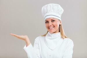 retrato de hermosa hembra cocinero gesticulando en gris antecedentes. foto