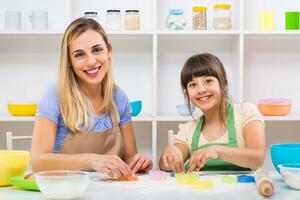 Happy mother and her daughter are making cookie together. photo