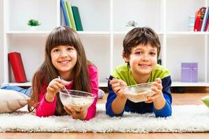 dos niños comiendo cereal en el piso foto