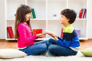 Little boy is giving a gift to a little girl photo