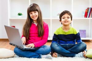 dos niños utilizando ordenador portátil foto