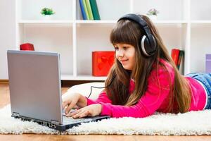 Little girl with headphones using laptop photo