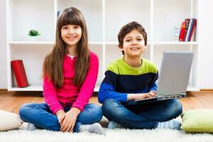dos niños sentado en el piso con un ordenador portátil foto