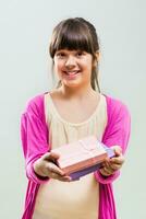 Little girl holding gifts on grey background photo