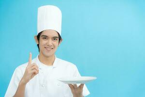 cocinando, culinario, masculino cocinero participación vacío lámina, masculino cocinero en gorro de cocinero y chaqueta terminado azul fondo, profesional, espectáculo, atender, cocinando, , gastrónomo, alimento, servicio, restaurante, presentación foto