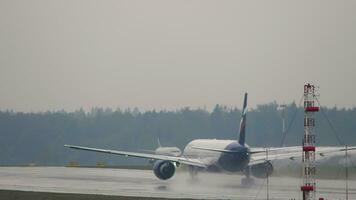 MOSCOW, RUSSIAN FEDERATION JULY 30, 2021 Boeing 777 of Aeroflot accelerating for takeoff at Sheremetyevo airport, rear view. Rain, wet runway, bad weather video