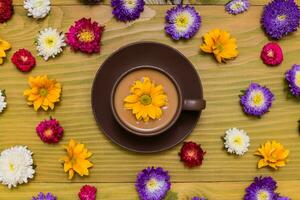 Image of cup of coffee with beautiful flowers on wooden background photo