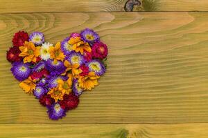 Image of heart shape made with beautiful flowers on wooden background photo