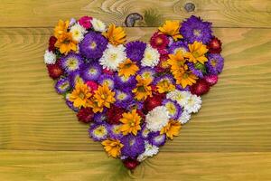 Image of heart shape made with beautiful flowers on wooden background. photo