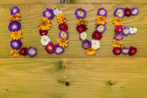 Image of word love made of beautiful flowers on wooden background photo