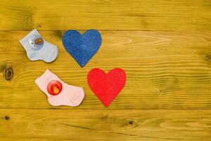 Hearts, baby socks and pacifier on a wooden table photo