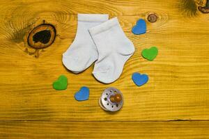 Text it's a boy with baby supplies and heart shapes on wooden table photo