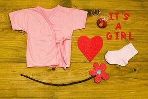 Text it's a girl with baby supplies and heart shape  on wooden table photo
