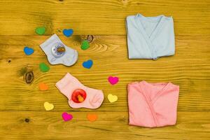 Baby supplies for  boy and girl and heart shapes on wooden table.Baby announcement concept photo