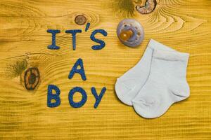 Text it's a boy with baby supplies  on wooden table photo
