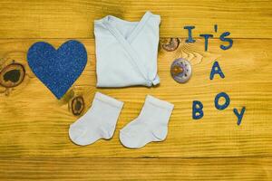 Text it's a boy with baby supplies  on wooden table photo