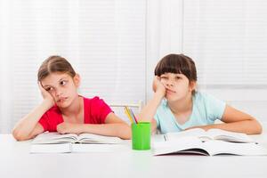 Sad little girls must stay at home and do their homework,but they would rather play outside. photo