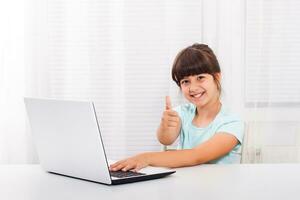 Cute little girl is using laptop.and showing thumb up. photo