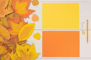 two blank papers with autumn leaves on a wooden table photo