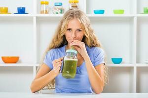 Beautiful girl enjoys drinking smoothie at her home photo