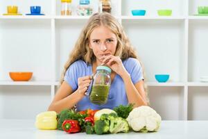 Beautiful girl enjoys drinking smoothie at her home photo