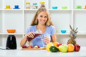 Beautiful girl enjoys making smoothie at her home photo