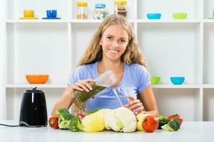 Beautiful girl enjoys making smoothie at her home photo