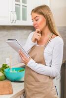 Beautiful woman reading cookbook while making a meal photo