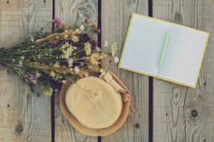 Beautiful bouquet of flower,notebook and  hat on wooden table photo