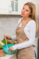 enojado mujer en pie en su cocina mientras haciendo comida foto