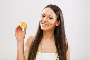 Beautiful brunette woman holding slice of lemon photo