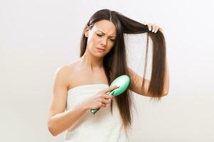 Image of angry woman brushing her hair on gray background photo