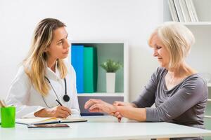 Senior patient telling female doctor how she is having wrist pain photo