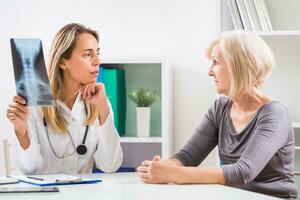 Female doctor is showing x-ray image to her senior woman patient photo