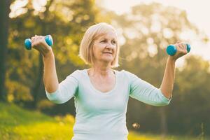Sporty senior woman exercising with weights outdoor photo