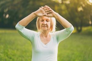 Senior woman enjoys exercise Tai Chi in the nature photo