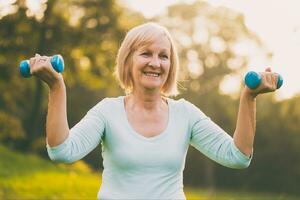 Sporty senior woman exercising with weights outdoor photo