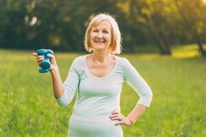 Portrait of sporty senior woman holding weights outdoor photo