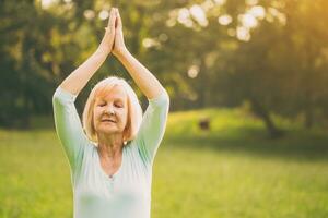 Senior woman enjoys meditating in the nature. photo