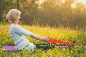 Sporty senior woman exercising with rubber band outdoor photo