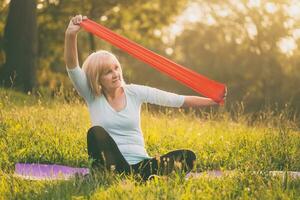 Sporty senior woman exercising with rubber band outdoor photo