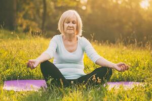 Senior woman enjoys meditating in the nature photo