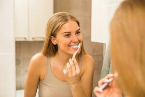 bella mujer cepillándose los dientes en el baño foto