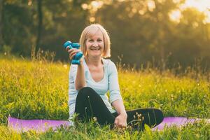 Portrait of sporty senior woman holding weights outdoor photo
