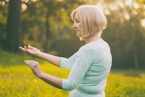 Senior woman enjoys exercise Tai Chi in the nature photo