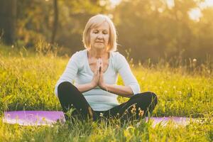 Senior woman enjoys meditating in the nature photo